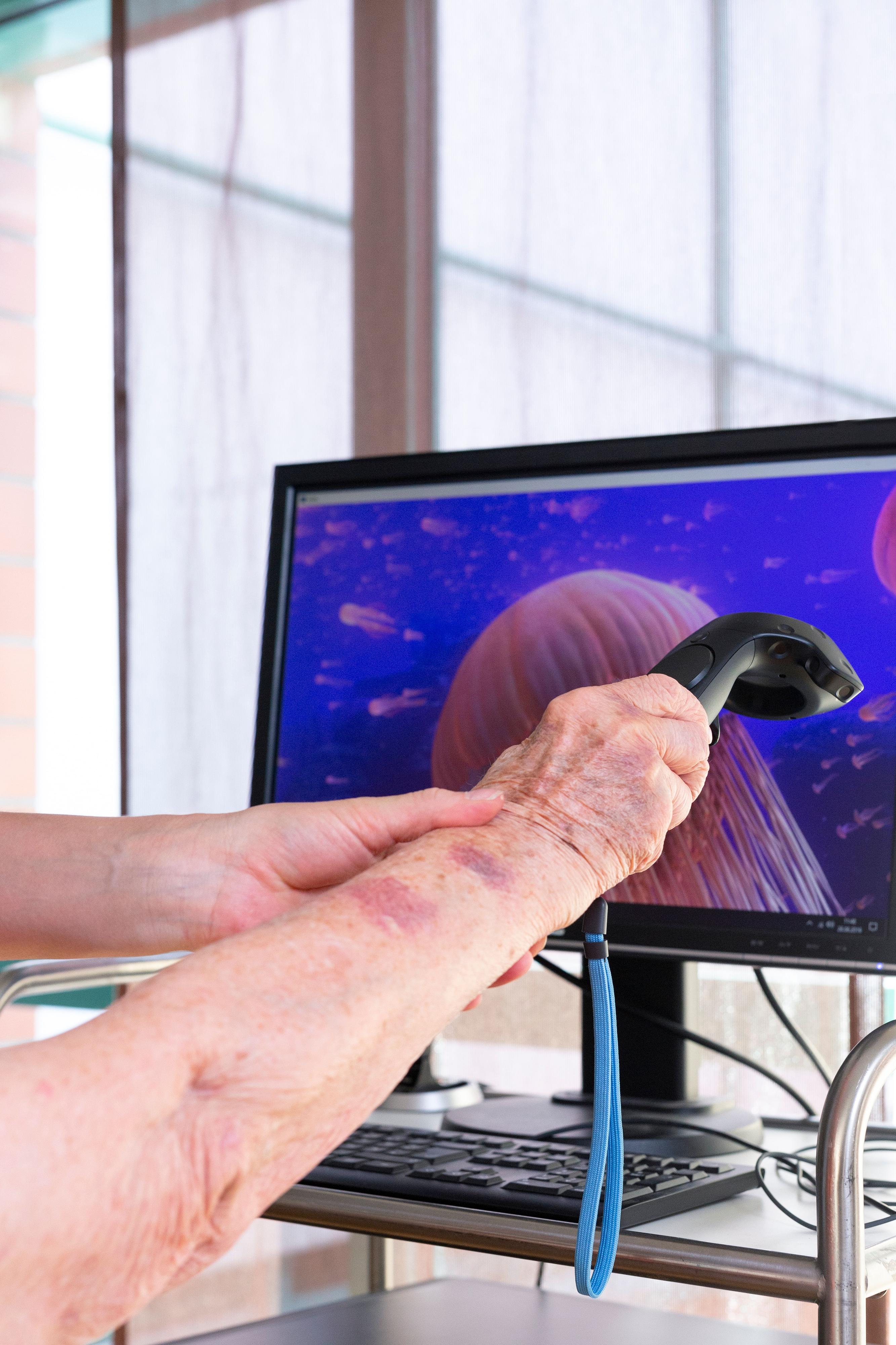 Eine Hand fährt mit einem elektrischen Gerät über einen Monitor.