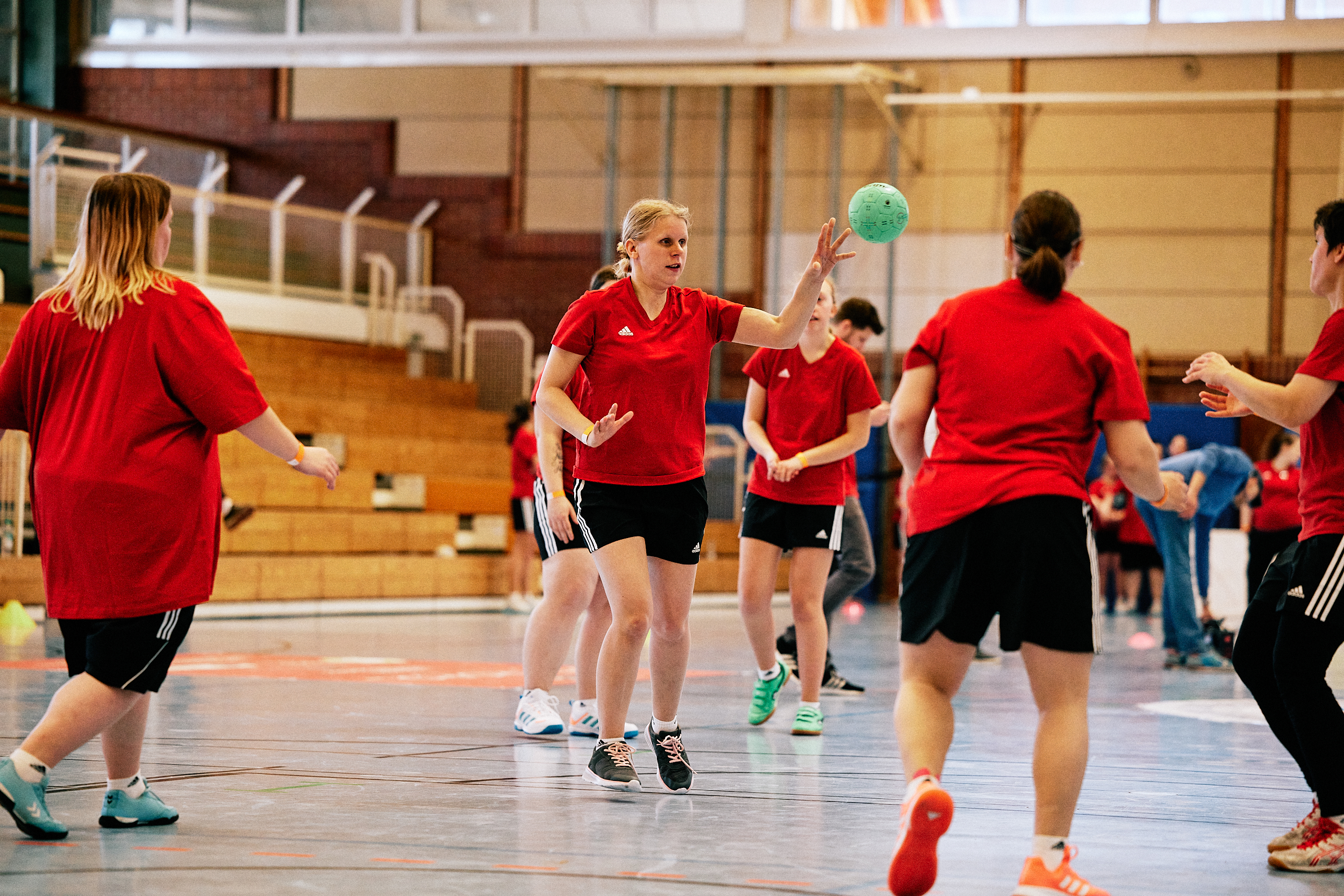 Fünf Handballerinnen auf einem Spielfeld werfen sich den Ball zu.