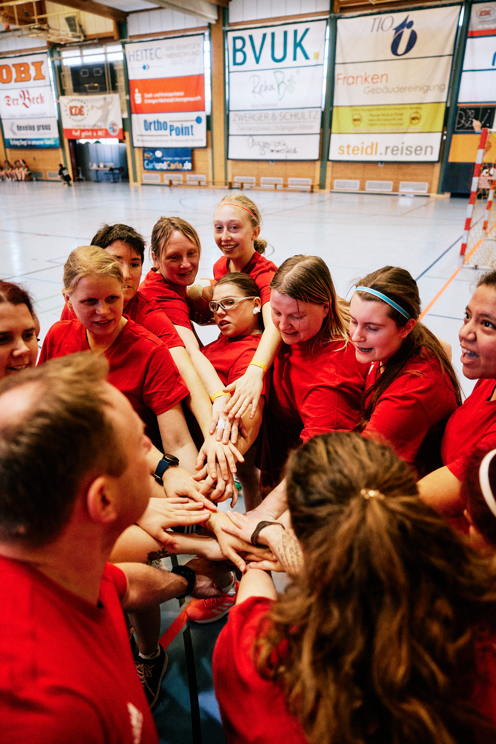 Die Handballerinnen stehen eng zusammen im Kreis und legen ihre Hände übereinander.
