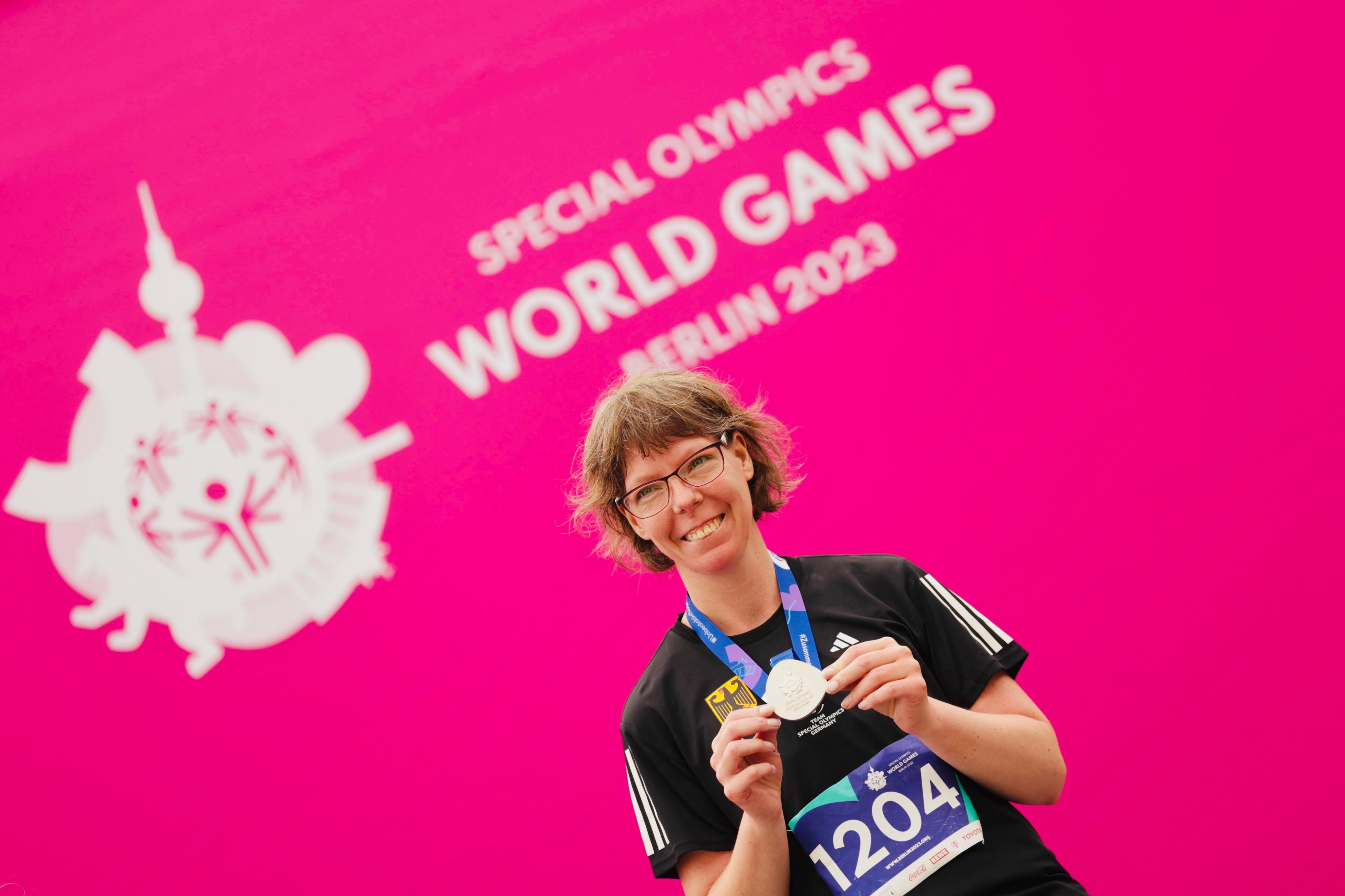 Annika Meissner mit Silbermedaille um den Hals vor pinker Wand mit SOWG-2023-Schriftzug