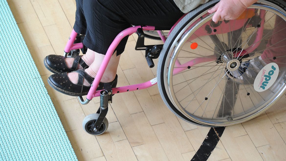 Rollstuhlfahrerin trainiert in der Halle das Überwinden von Kanten.