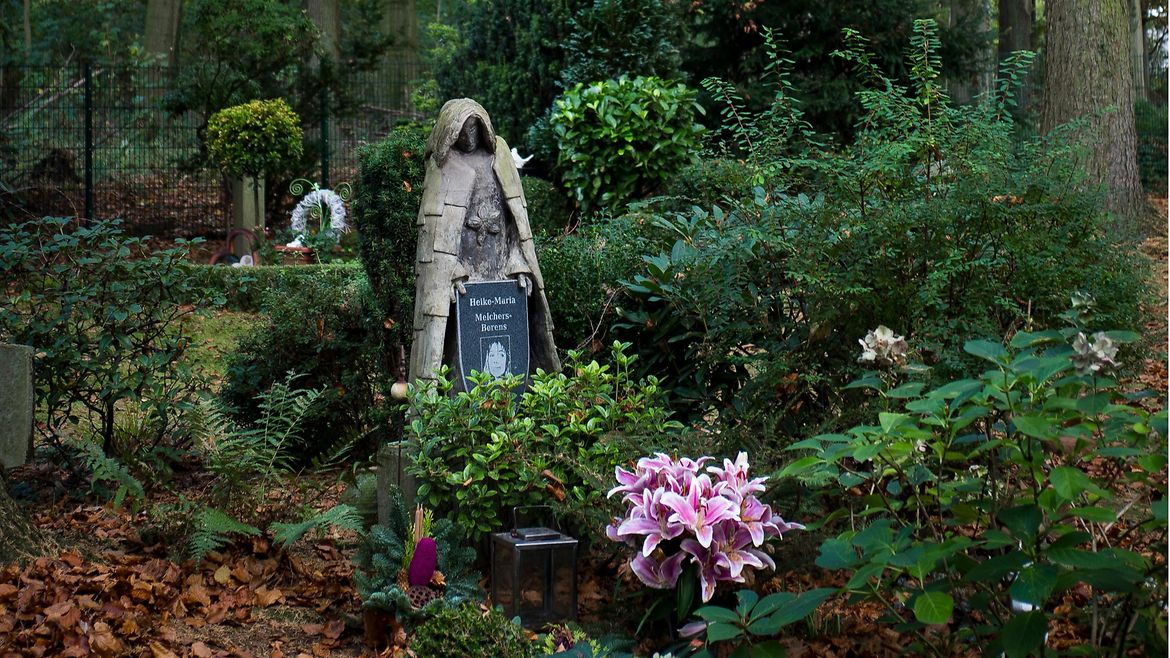 Ein Grabstein auf einem Waldfriedhof.