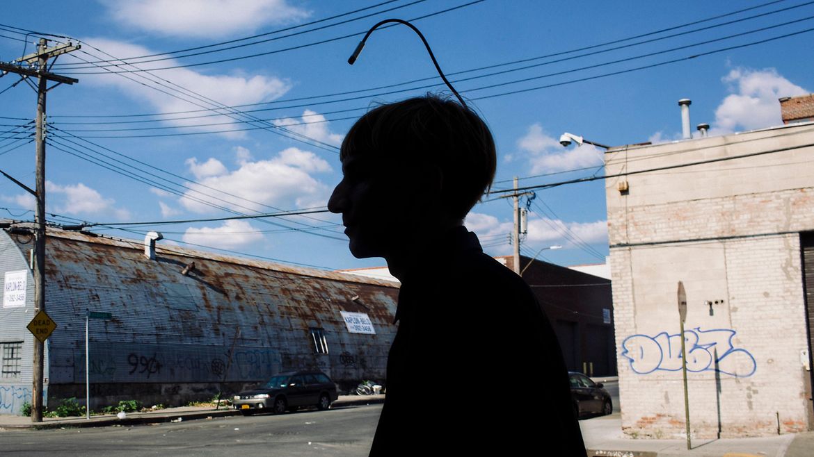 Die Shilouette eines Mannes im Profil, aus dessen Hinterkopf eine dünne, nach vorne gebogene Antenne ragt.