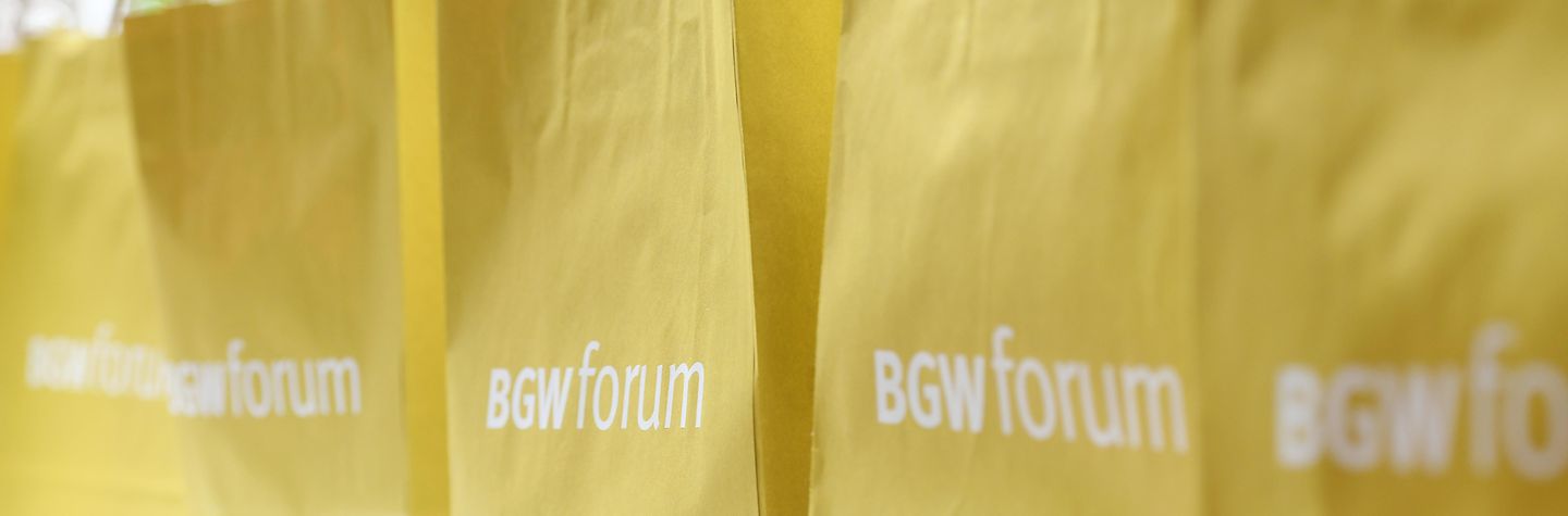 Weißer Logo-Schriftzug BGW forum auf gelben Papiertüten