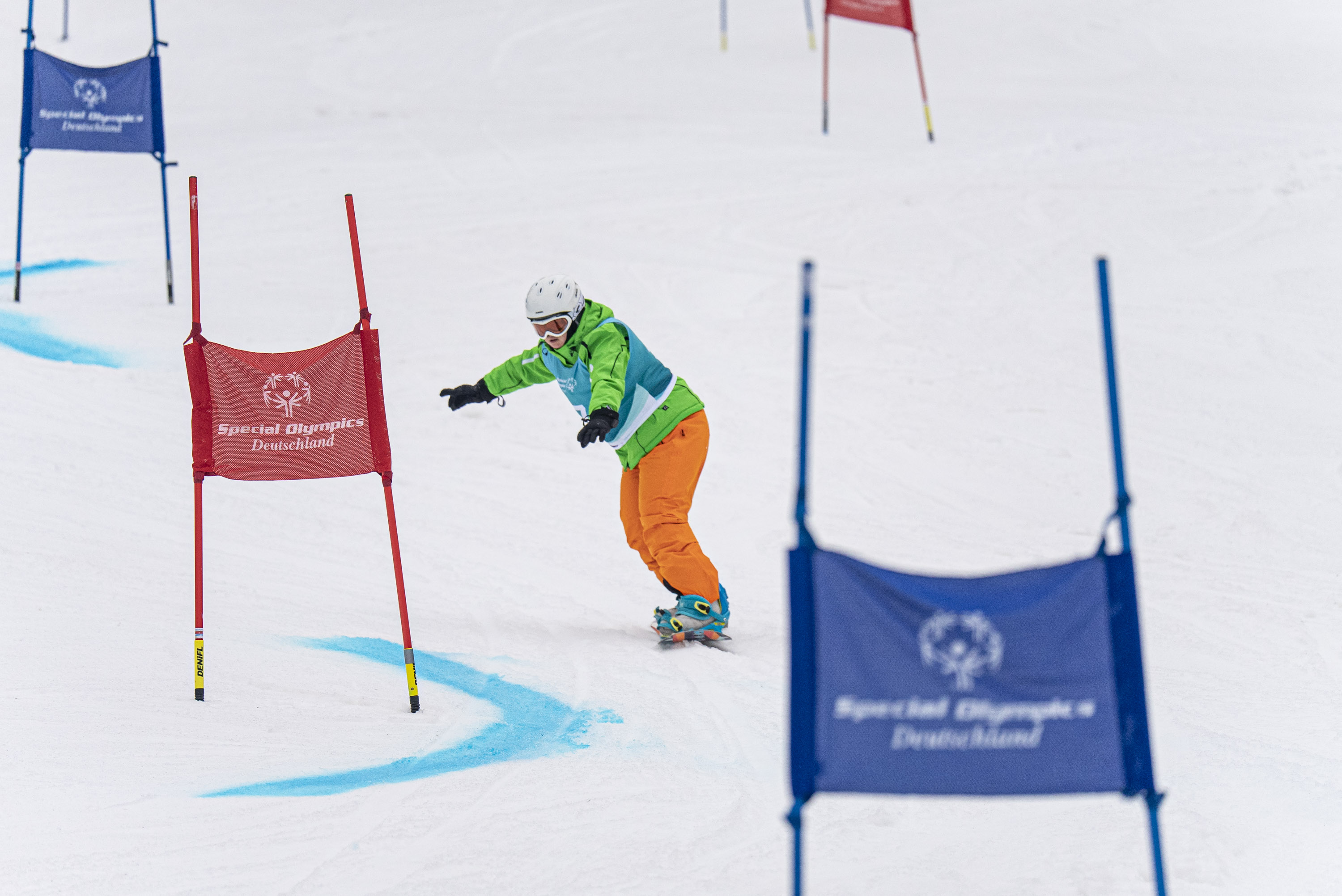 Ein Snowboarder auf einer Piste steuert zwischen SOD-Fahnen-Tore hindurch.