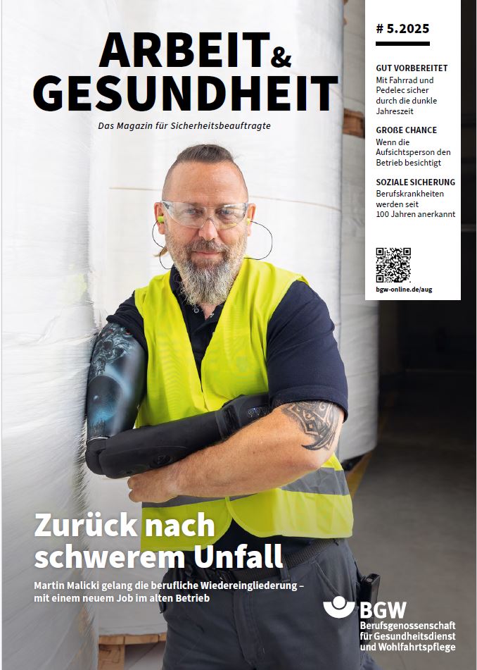 Titel des Magazins Arbeit & Gesundheit: Zwei Männer in einer Fabrikhalle, einer der Männer trägt Arbeitskleidung