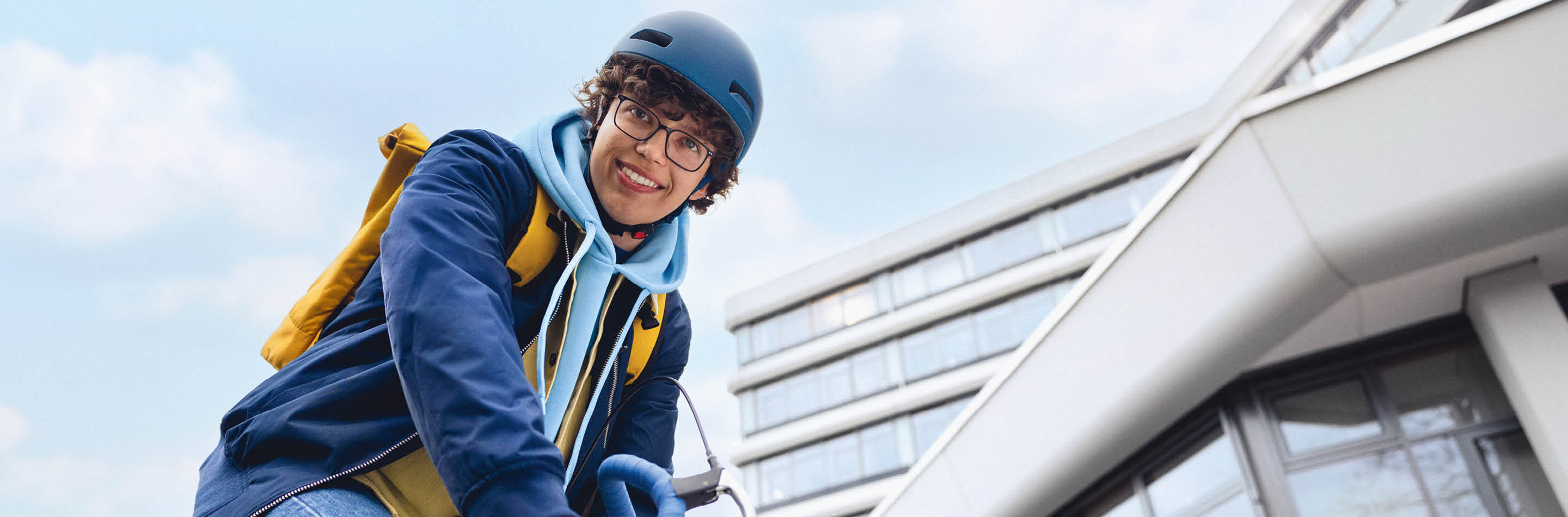Ein junger Mann sitzt lächelnd auf einem Fahrrad.