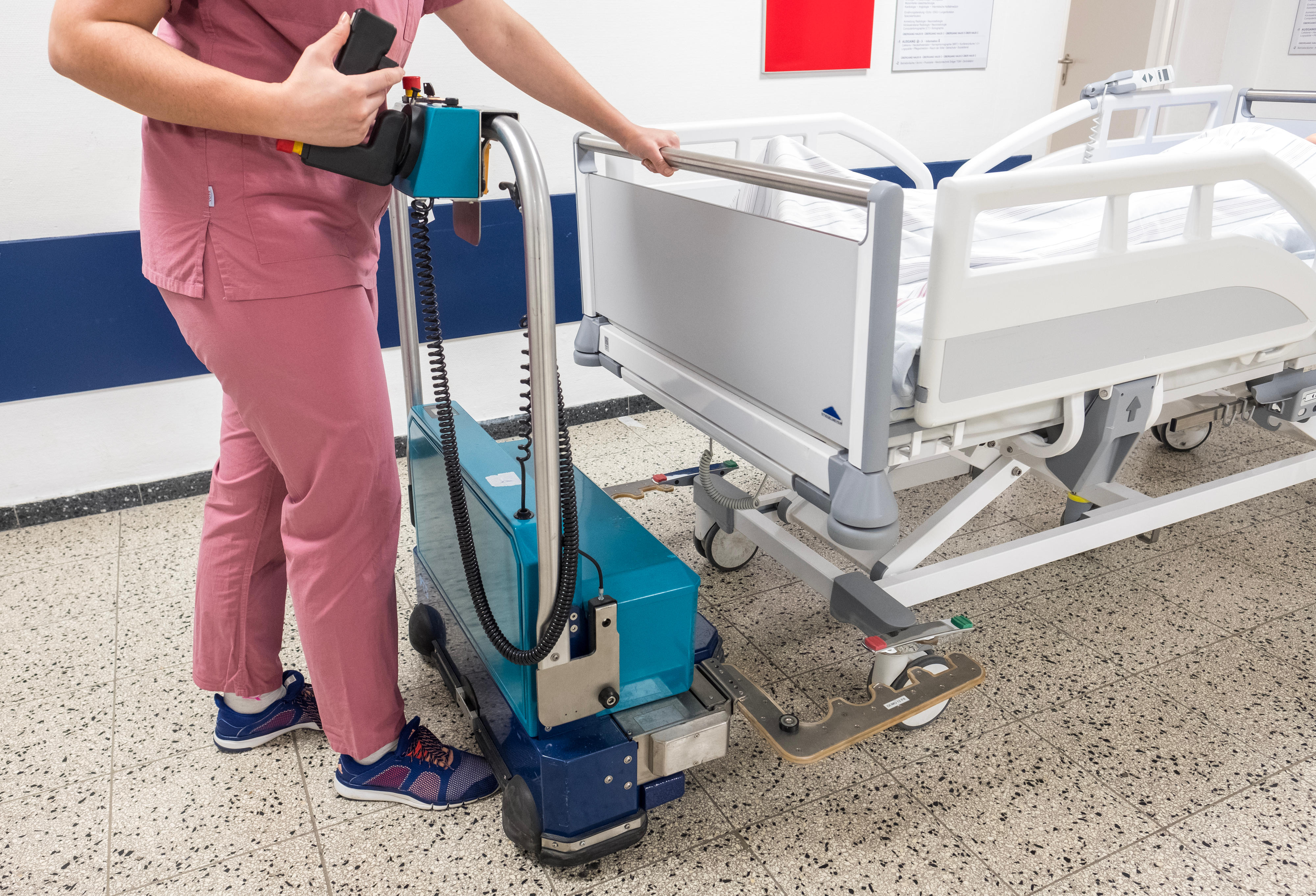 Eine Pflegekraft schiebt einen Bed Mover mit der Aufnahme unter ein Bett, um es anzudocken.