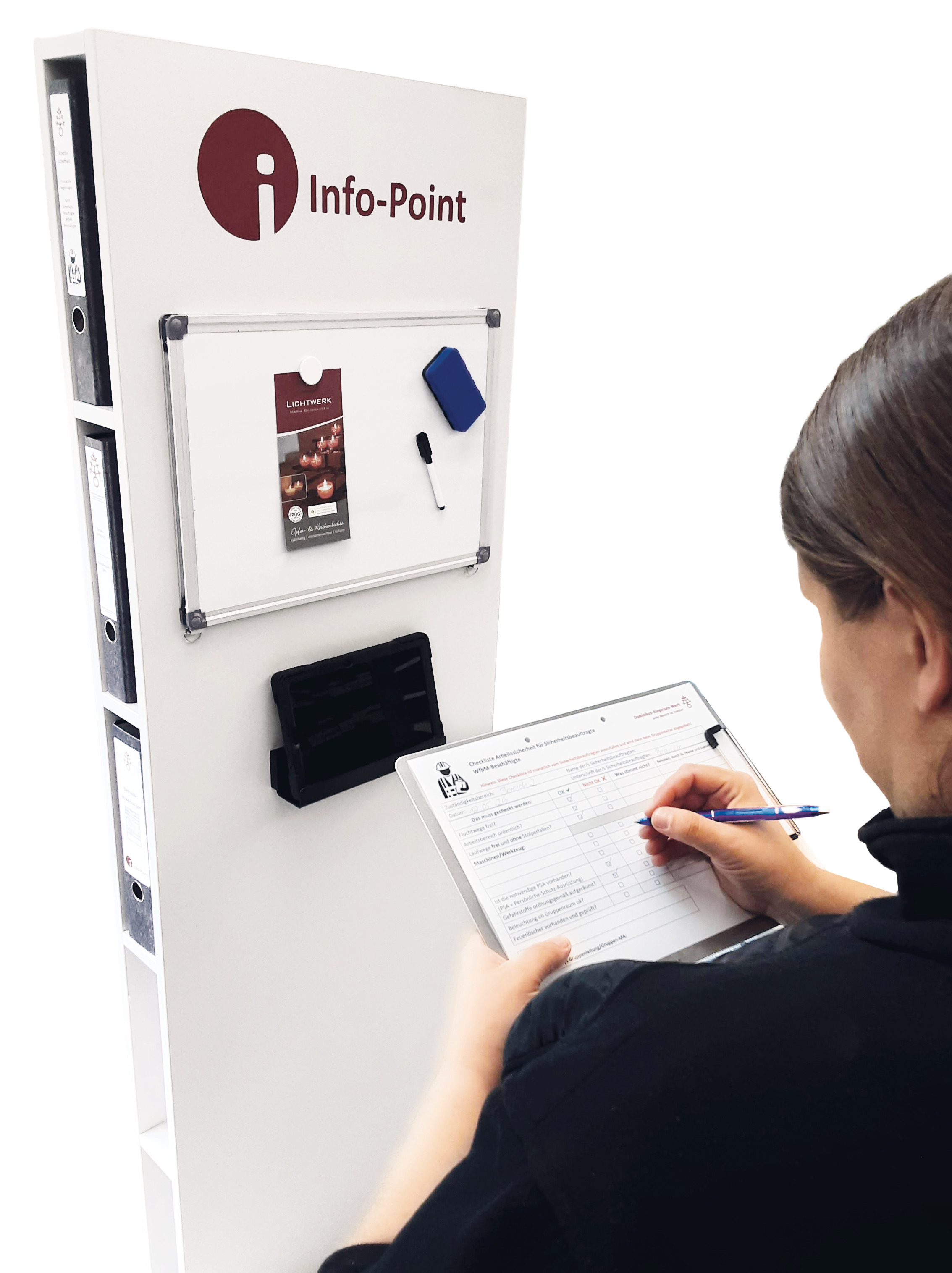 Frau steht mit Klemmbrett und Stift vor einer schmalen Regalwand, auf der "Info-Point" steht. In den Regalfächern an den Seiten stehen Papierordner, an der Front der Regalwand hängt eine Magnettafel, an der ein Stift, ein Putzschwamm und ein Flyer hängen. Darunter hängt ein Tablet.
