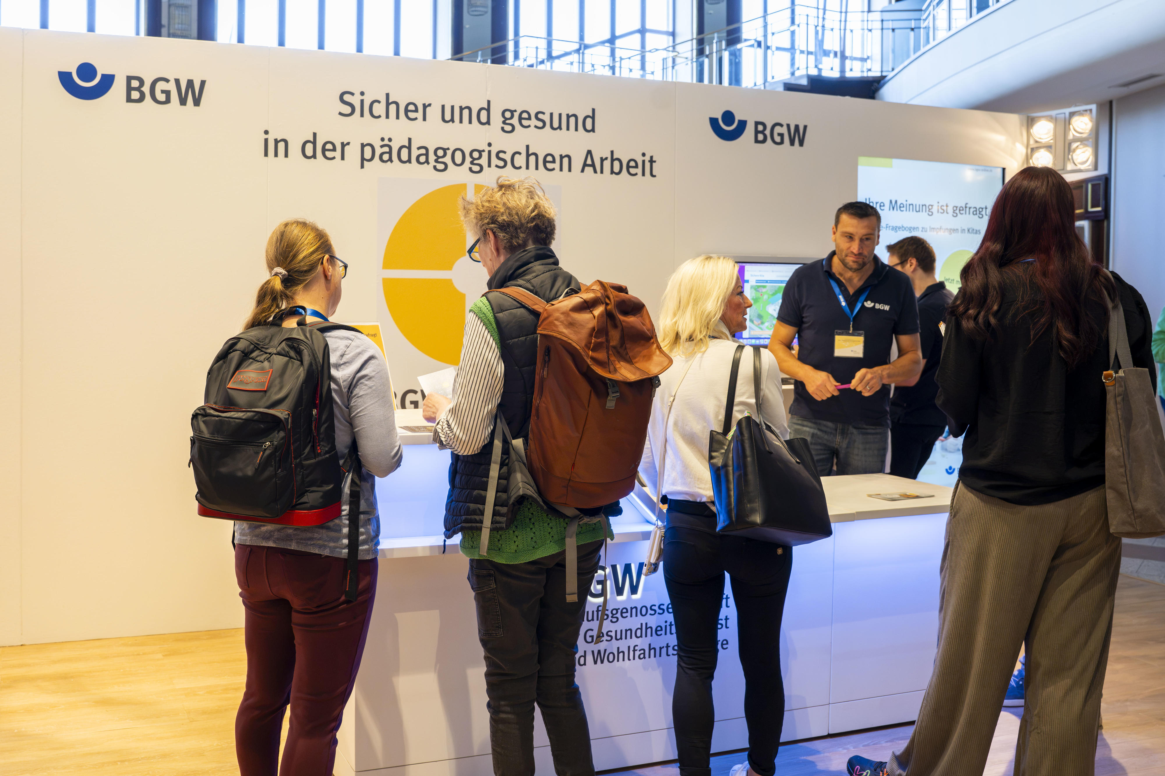 Mehrere Personen an der Infotheke BGW forum 2026 "Sicher und gesund in der pädagogischen Arbeit" in Köln.