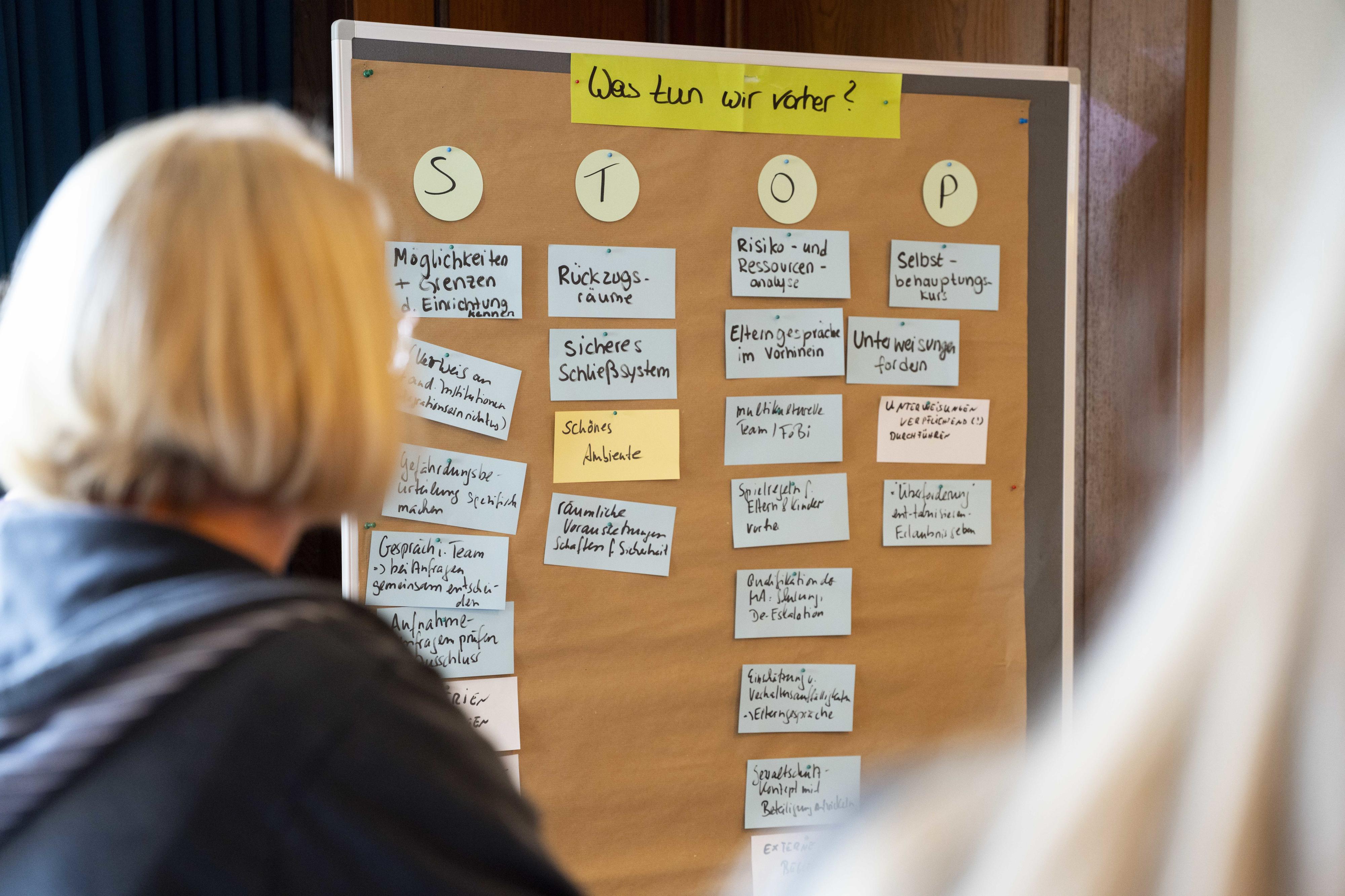Workshop-Situation zur „STOP-Methode“ auf dem BGW forum "Sicher und gesund in der pädagogischen Arbeit“ 2026. Eine Frau blickt auf eine Metaplanwand mit angepinnten Moderationskarten, dessen Überschrift "Was tun wir vorher?" lautet. Darunter hängen Moderationskarten mit den Buchstaben "S", "T" ,"O" und "P". Unter jedem Buchstaben hängen mehrere Moderationskarten mit Einzelmaßnahmen.