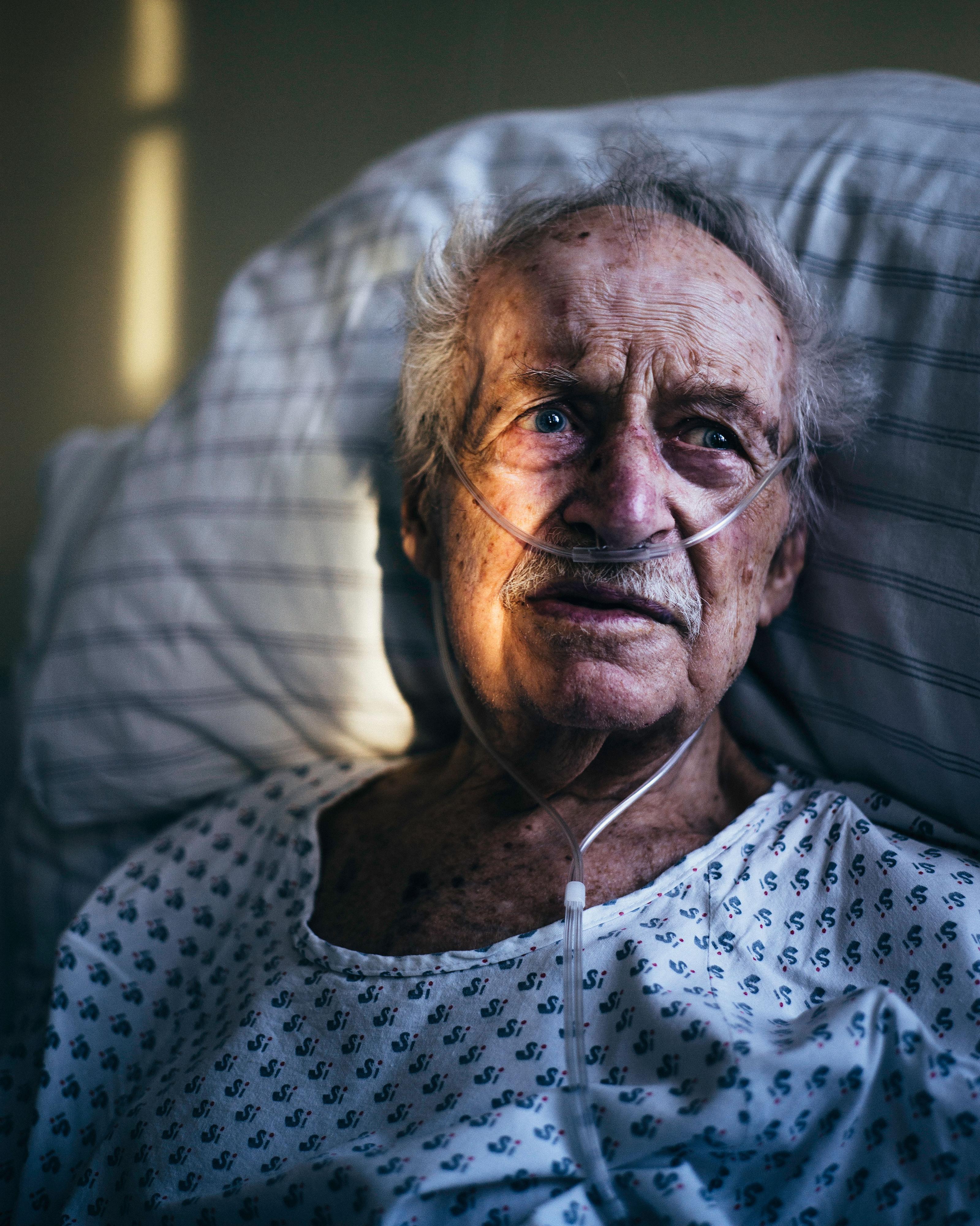 Ein älterer Mann liegt in einem Krankenhausbett - er bekommt Sauerstoff durch Schläuche in der Nase.