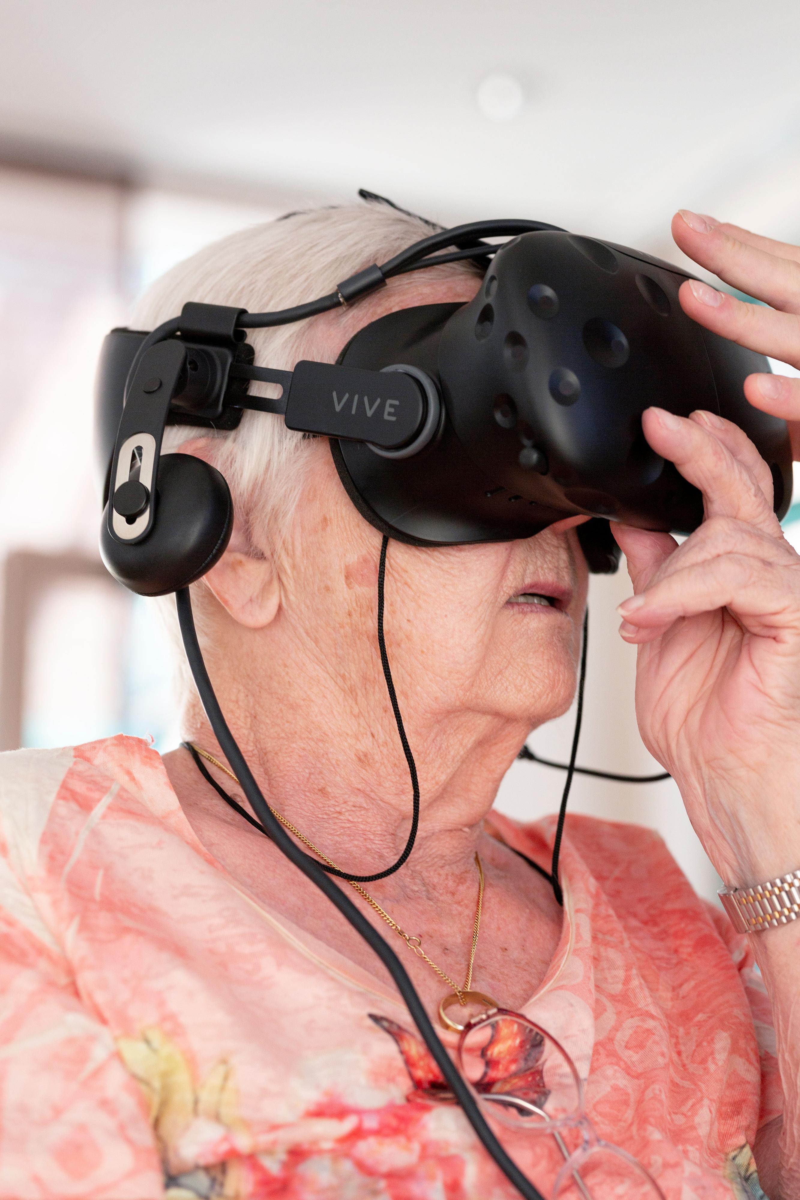 Eine ältere Frau hat eine VR-Brille aufgesetzt.