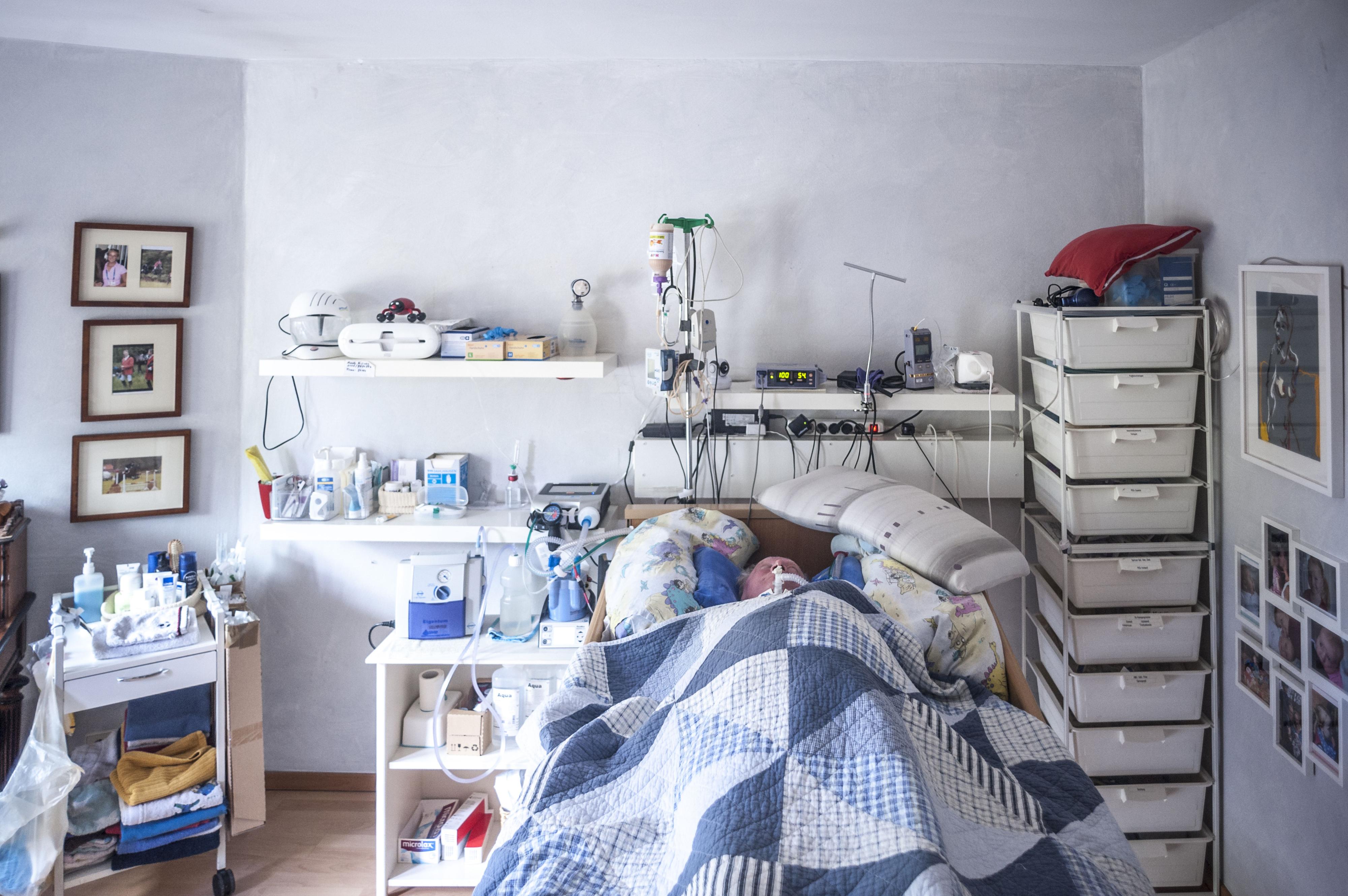 Ein älterer Mann liegt in einem Bett, umgeben von medizinischen Geräten.