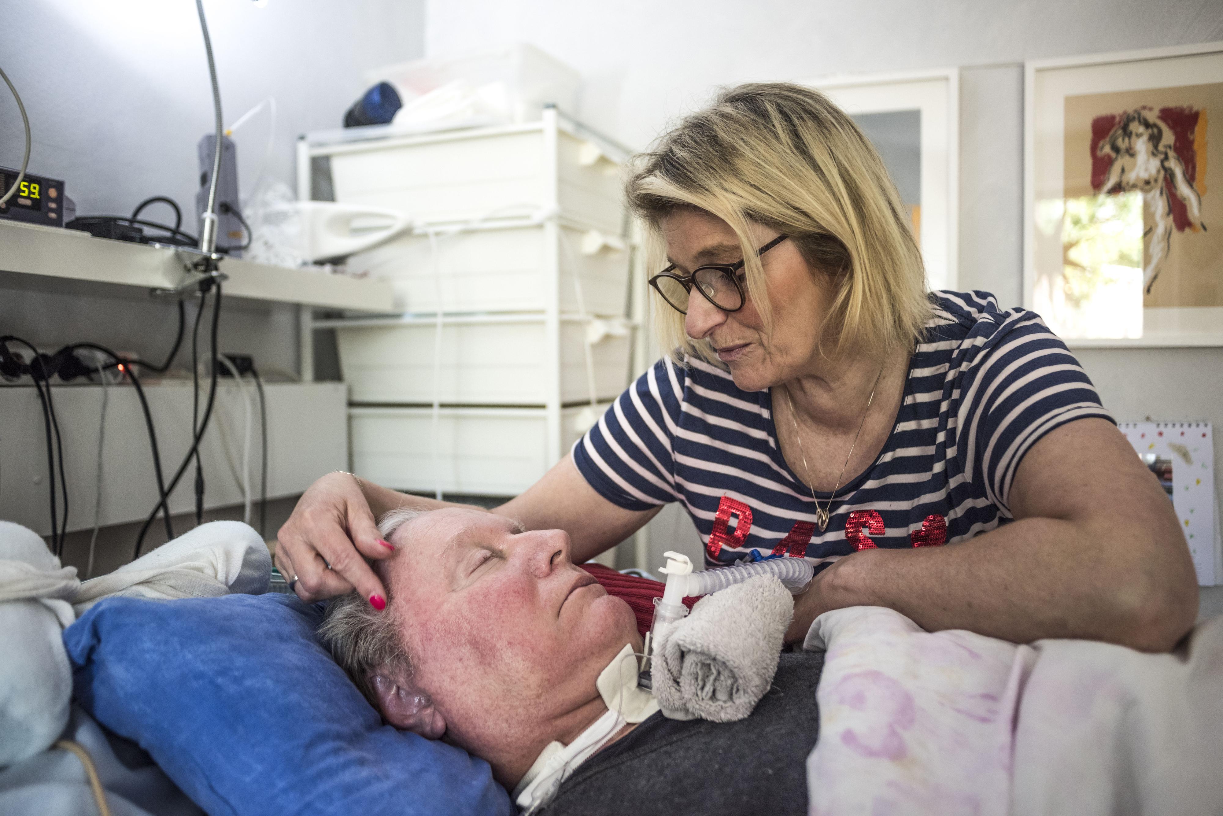 Eine Frau beugt sich über einen Mann im Bett.