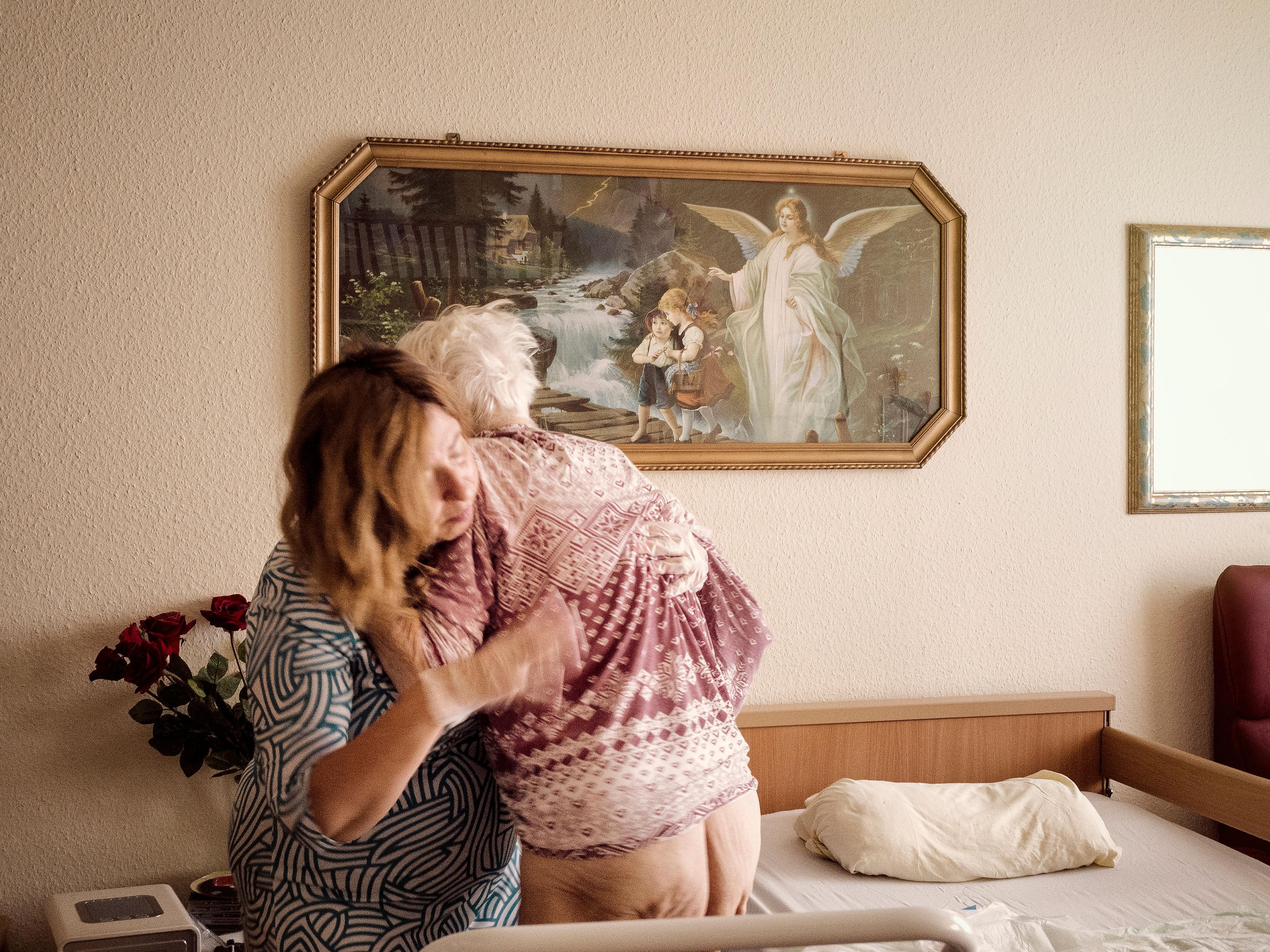 Eine Frau hilft einer älteren Frau ins Bett.