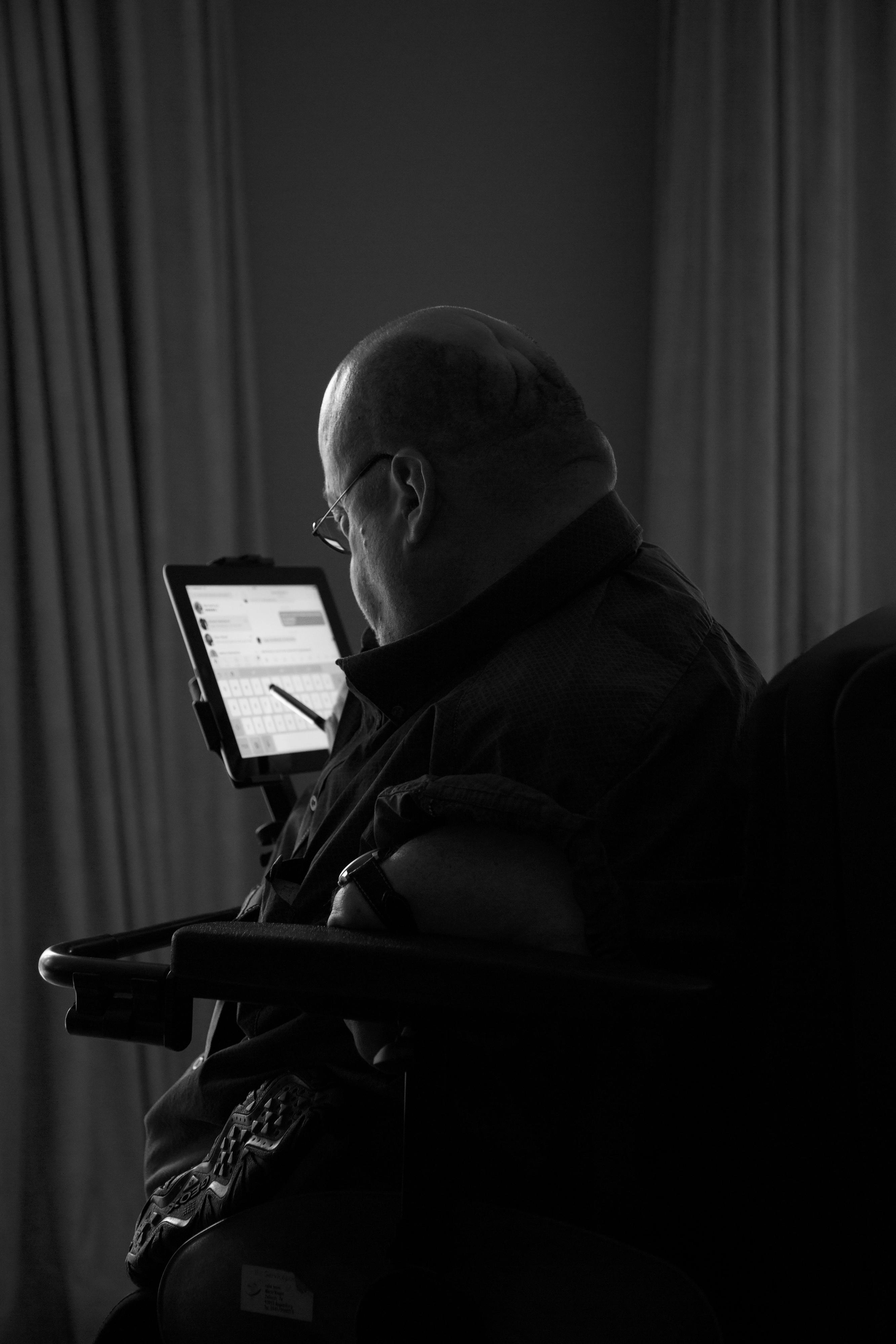 Ein Mann im Rollstuhl arbeitet an einem tablet.