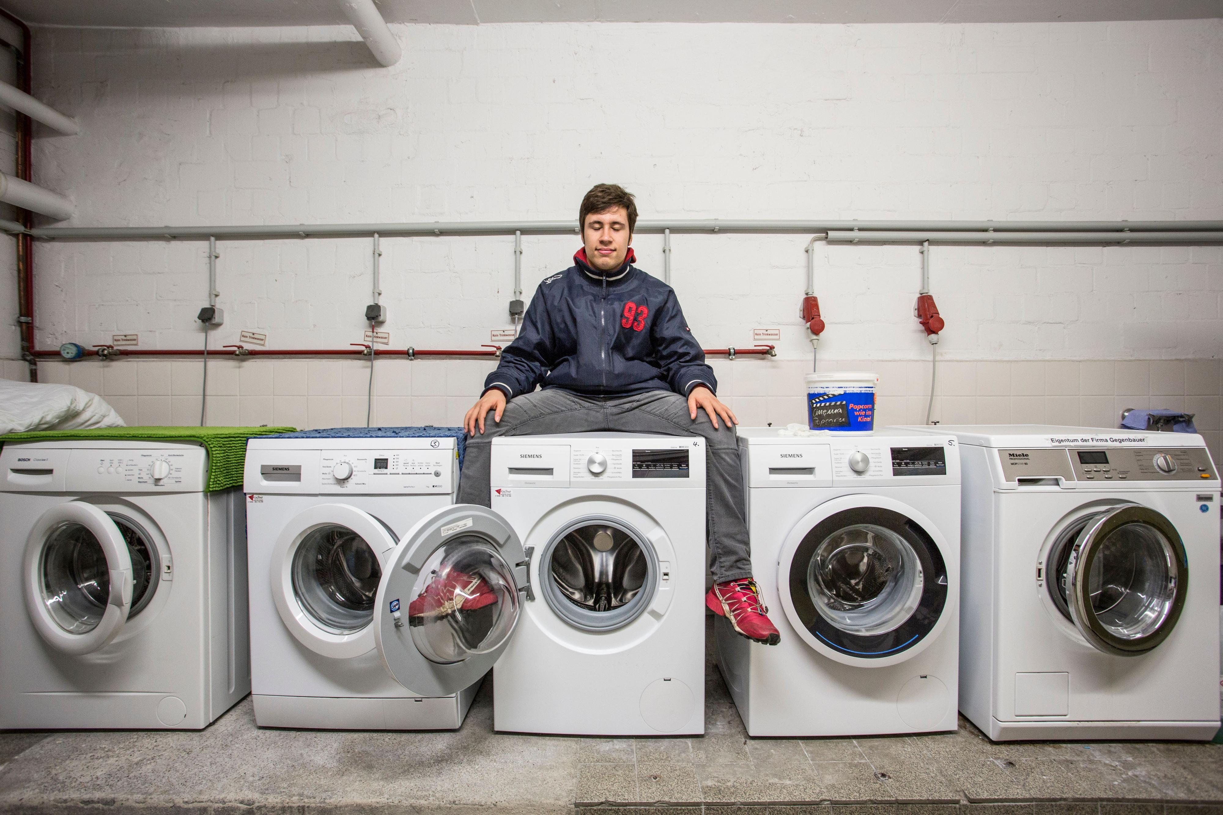 Ein Mann sitzt auf der mittleren von fünf Waschmaschinen.