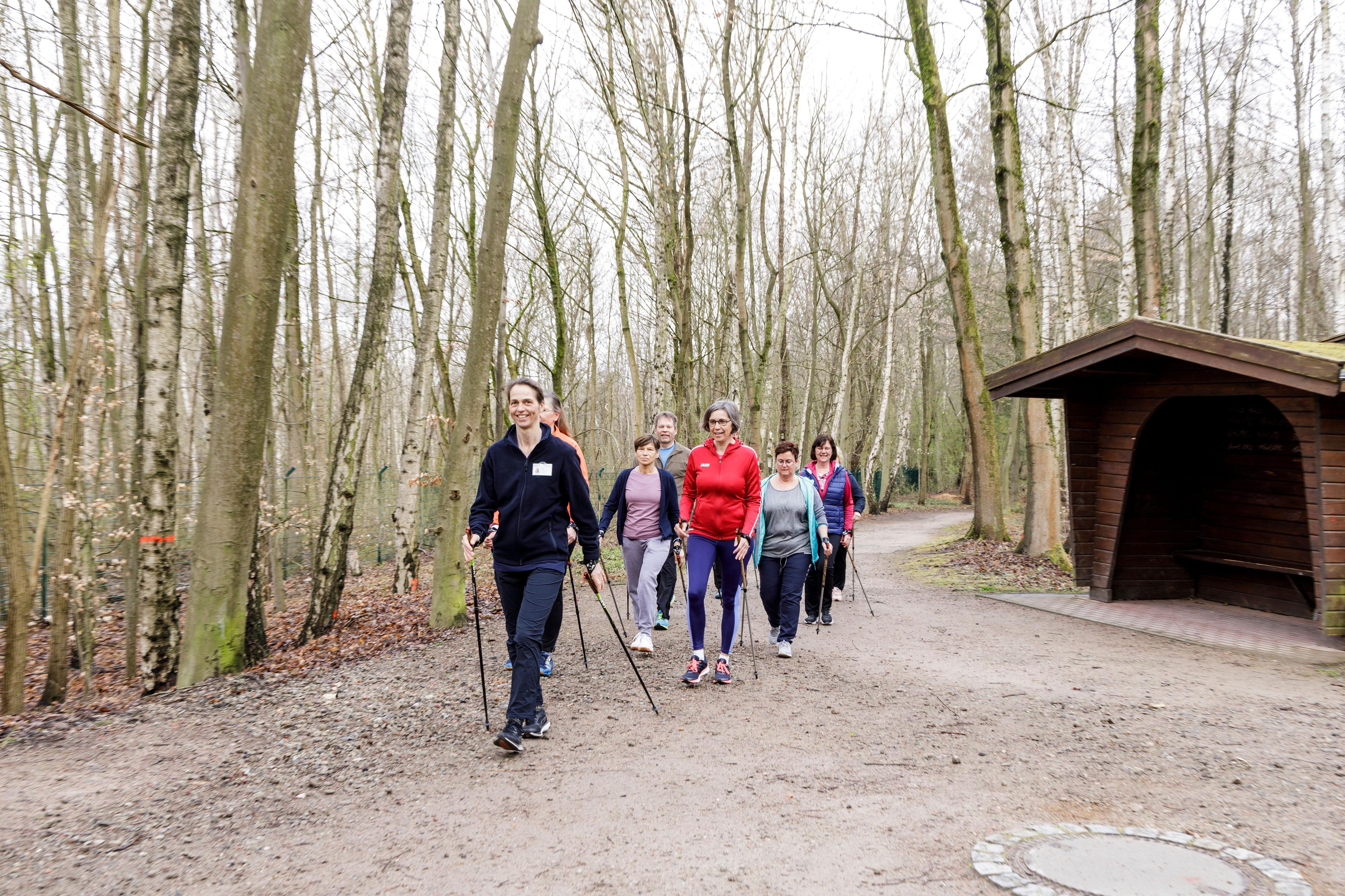 Eine Gruppe von Teilnehmenden des BGW Rückenkollegs nimmt an einer Nordic-Walking-Runde auf dem Gelände des BG Klinikums Hamburg unter Anleitung einer Trainerin teil.