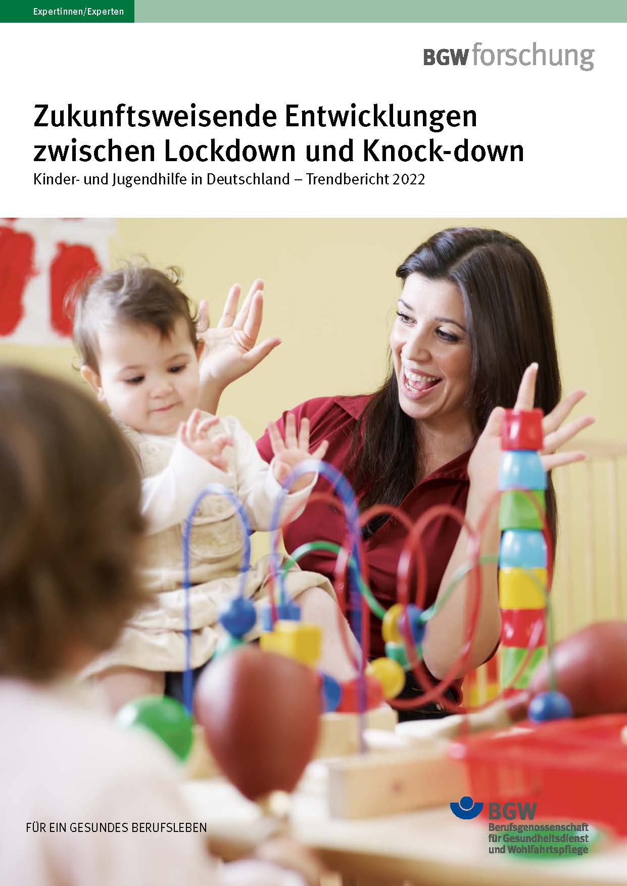 Titelbild Broschüre: Baby auf dem Schoß einer Frau - beide gestikulieren lachend - im Vordergrund Spielzeug.