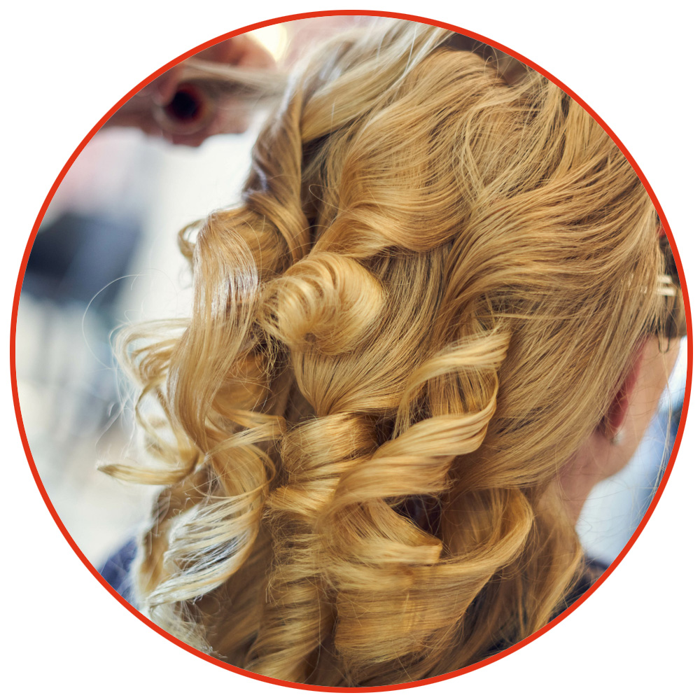 Einer blonden , langhaarigen Frau werden im Friseursalon Locken gemacht