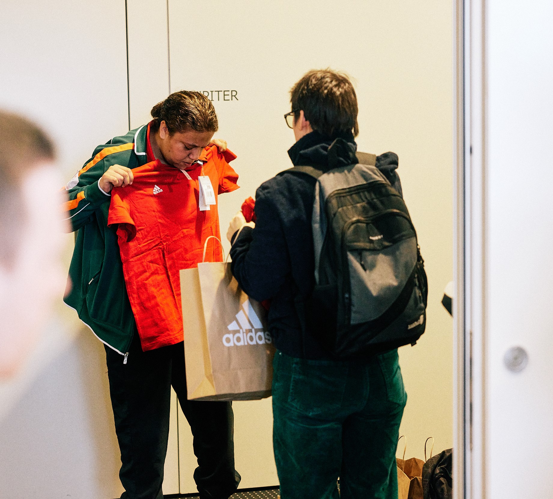 Sportlerin Crisdaian Abel hält ein T-Shirt vor ihren Körper. Neben ihr hält Gaby Grzonkowski eine Adidas-Tüte.