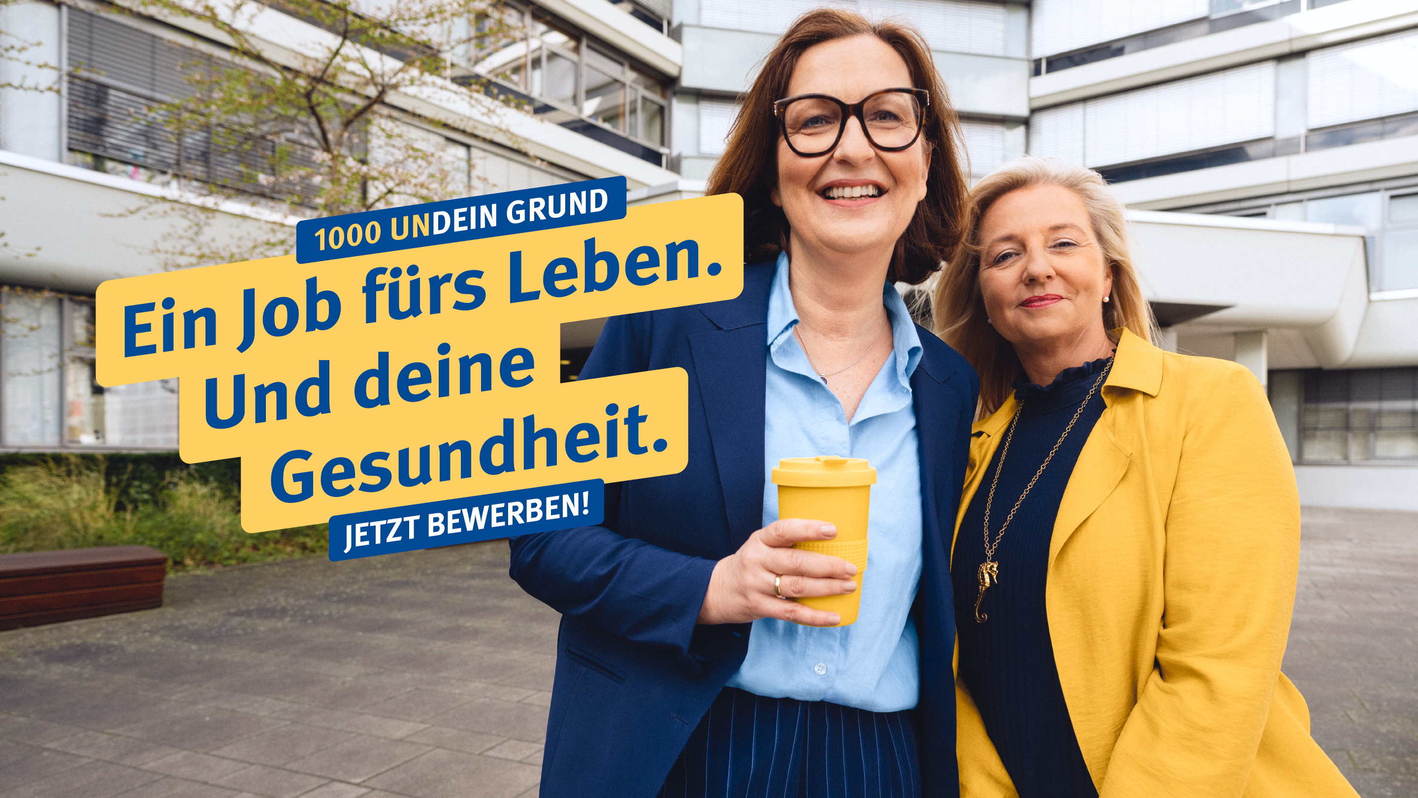 Zwei Frauen stehen lächelnd vor einem Bürogebäude, dazu der Text: "1000 undein Grund – Ein Job fürs Leben. Und deine Gesundheit. Jetzt bewerben!"