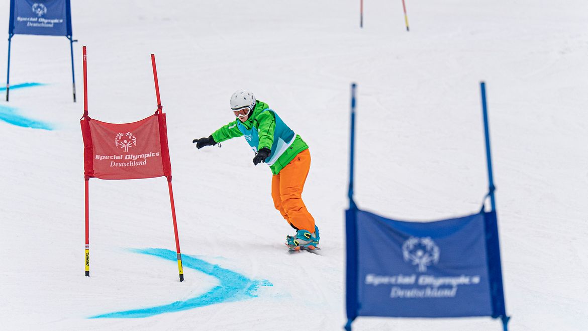 Ein Snowboarder auf einer Piste steuert zwischen SOD-Fahnen-Tore hindurch.