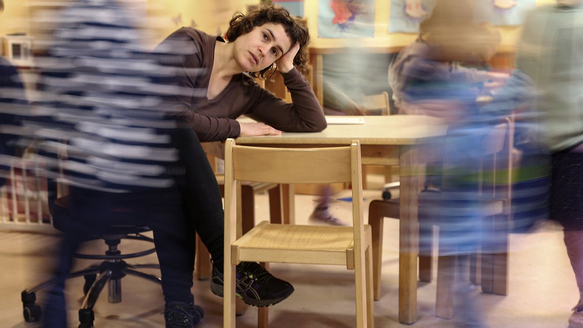 Die Frau am Tisch ist scharf zu sehen, die Kinder um sie herum unscharf