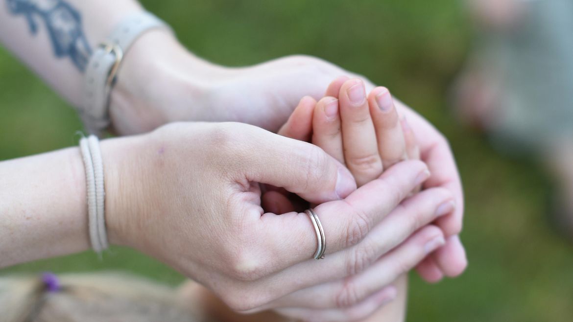 Die Hände einer Frau umschließen die hochgestreckten Hände eines Mädchens