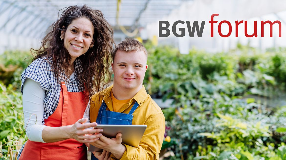 Eine Frau steht neben einem Jungen mit Down-Syndrom, der ein Tablet in der Hand hält, in einem Gewächshaus vor grünen Pflanzen. Beide tragen Arbeitskleidung und lächeln in die Kamera. Oben links steht der Schriftzug "BGW forum".