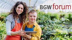 Eine Frau steht neben einem Jungen mit Down-Syndrom, der ein Tablet in der Hand hält, in einem Gewächshaus vor grünen Pflanzen. Beide tragen Arbeitskleidung und lächeln in die Kamera. Oben links steht der Schriftzug "BGW forum".