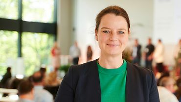 Eine Frau mittleren Alters lehnt an einem Bistrotisch