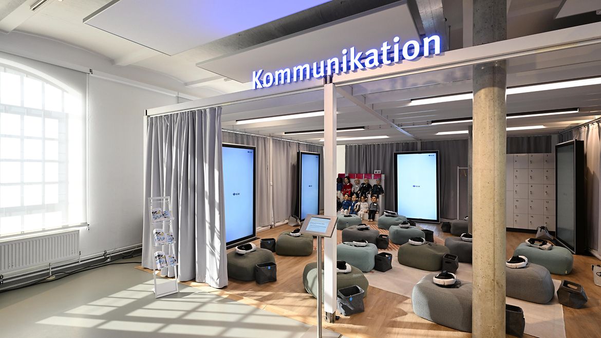 Ausstellungsraum Kommunikation, mit Sitzblöcken, auf denen VR-Brillen liegen. 