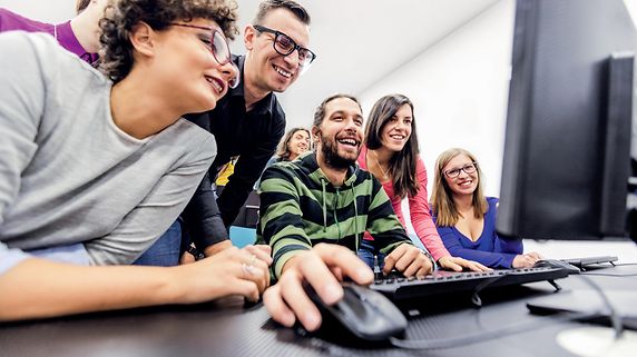 Eine Gruppe von fröhlichen Menschen vor einem Computer.