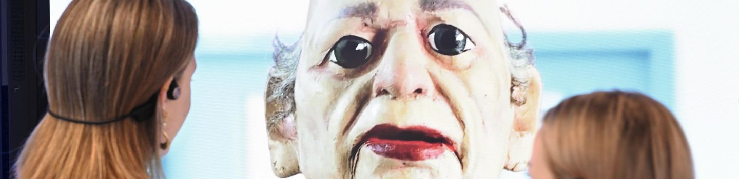 Überlebensgroße Puppe, der zwei Personen gegenüberstehen