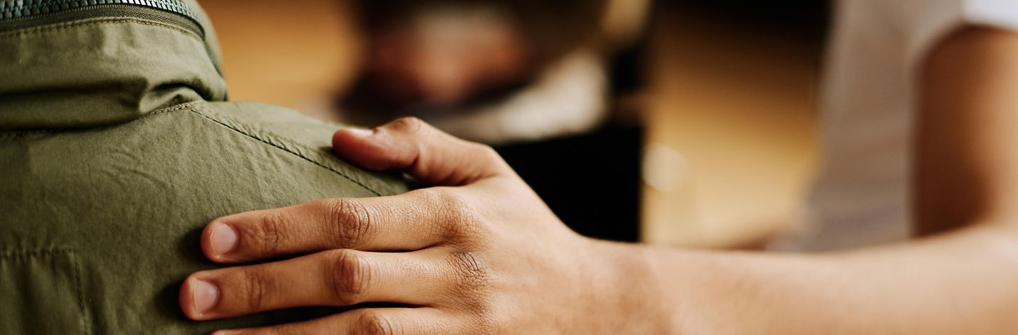 Hand of young supportive man consoling his friend or one of attendants with post traumatic syndrome caused by dramatic life event