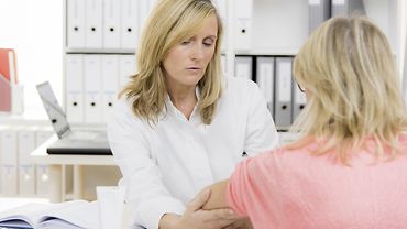 Eine Ärztin untersucht in einer Praxis den Arm einer Patientin