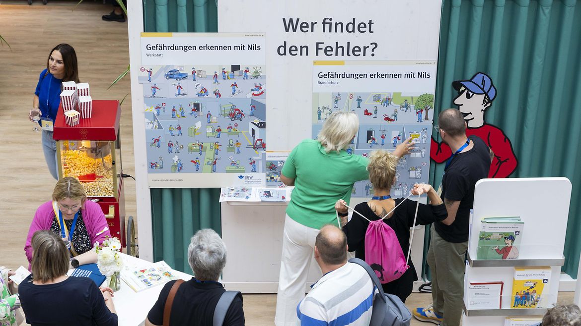 Mehrere Personen schauen auf eine Wand mit Plakaten