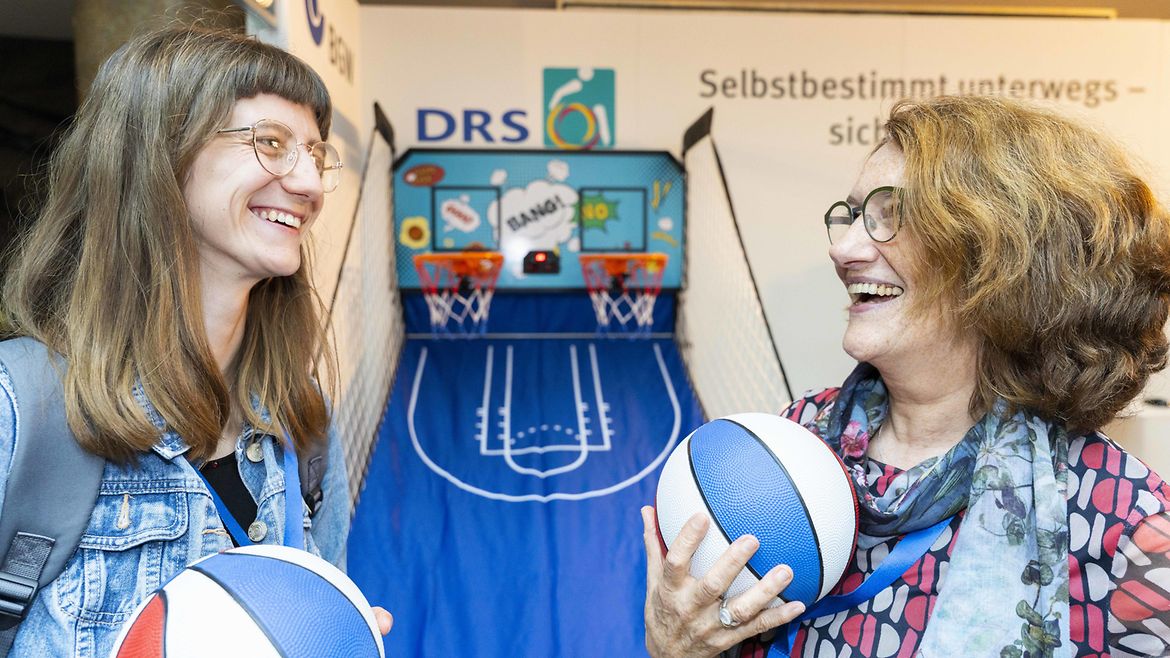 Zwei Personen mit kleinen Basketbällen vor Basketball-Körben
