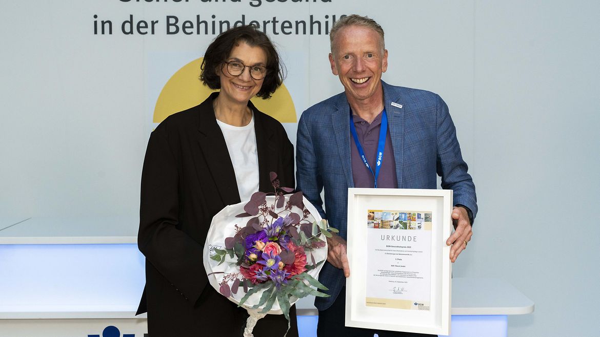 Katja Schimanski mit einem Blumenstrauß und Markus Grotthoff mit der gerahmten Urkunde für den 3. Preis, der an die Stift Tilbeck GmbH aus Havixbeck geht.