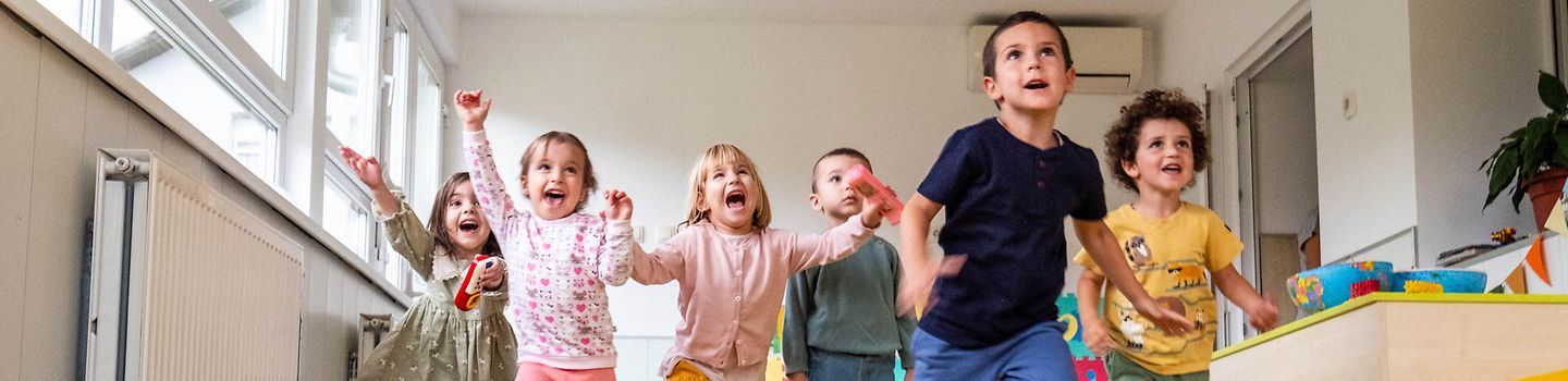 Fröhliche und tobende Kinder im Spielzimmer eines Kindergartens
