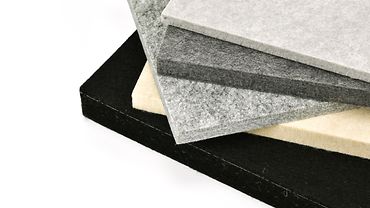 Fünf übereinander gestapelte Filzmatten in verschiedenen Stärken und diversen Farbnuancen von Schwarz bis hellgrau