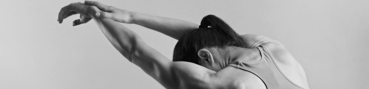 Rückenansicht einer Frau im Sport-BH, die Ihre Hände über den Kopf streckt und sich dehnt.