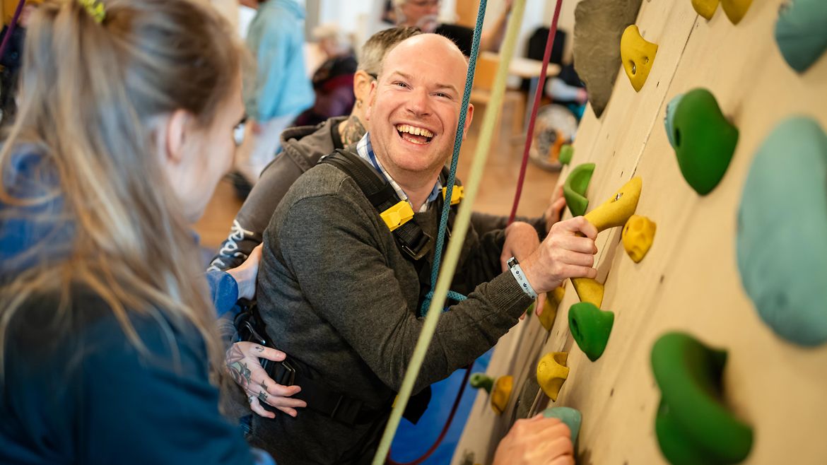 Zwei Fachkräfte klettern im Tandem mit einer Person mit Beeinträchtigung.
