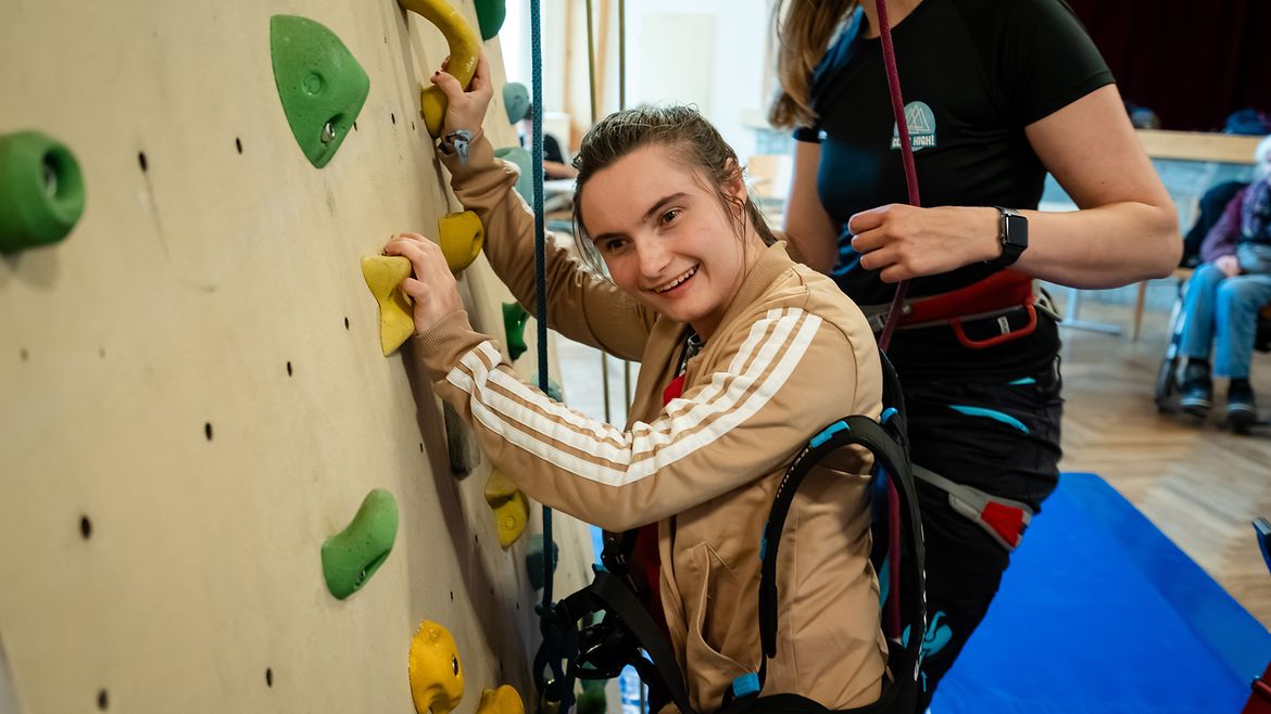 Eine Teilnehmerin steigt mit Seilen gesichert in die Kletterwand ein.
