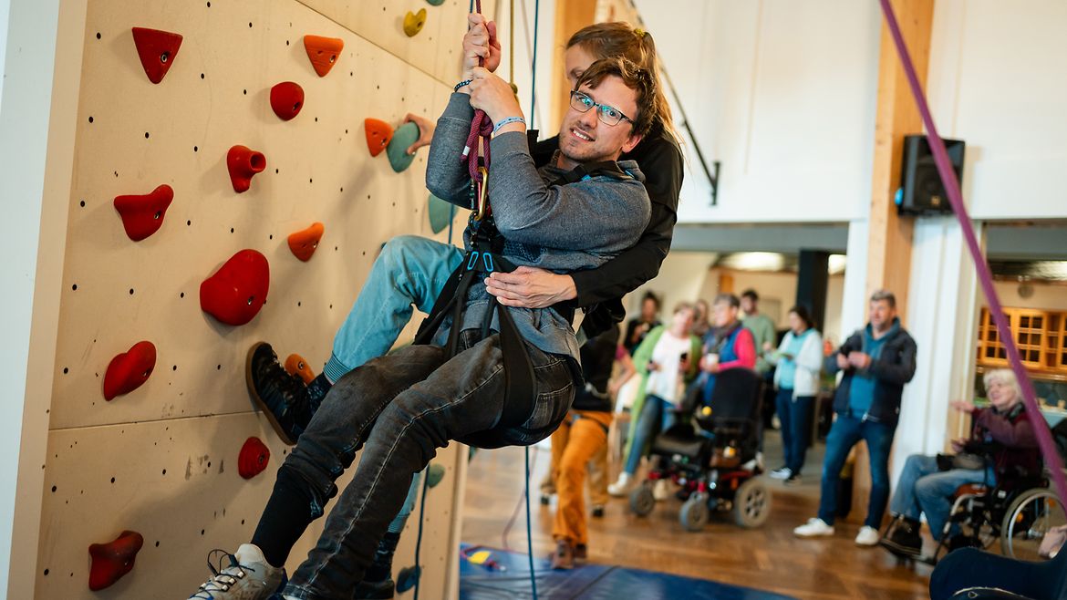 Zwei Buddys klettern gemeinsam an der Kletterwand.