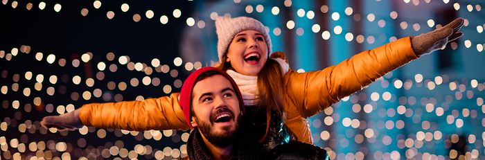 Junges Paar auf Weihnachtsmarkt vor vielen winzigen Leuchten