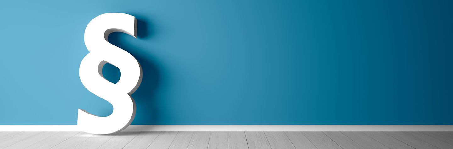 Ein Paragraphen-Modell lehnt an einer blauen Wand