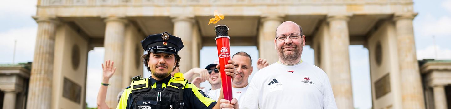 Ein Läufer mit einer Fackel und Polizist vor dem Brandenburger Tor.
